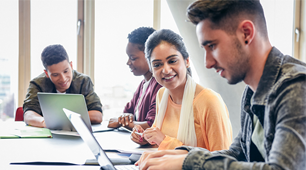 Young man using laptop with female student watching and smiling
